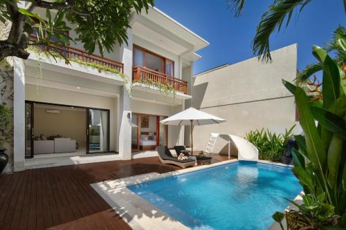a villa with a swimming pool in front of a house at Daha Mansions Seminyak in Seminyak