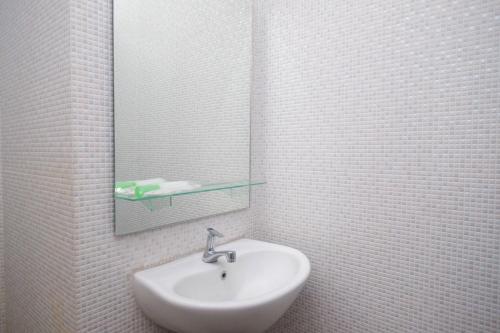 a white bathroom with a sink and a mirror at RedDoorz Apartment near Exit Toll Colomadu in Solo