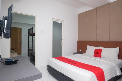 una camera da letto con un grande letto bianco con cuscini rossi di RedDoorz Apartment near Exit Toll Colomadu a Solo