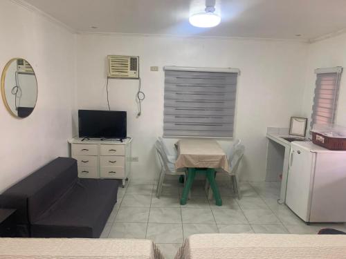 a room with a table and a desk with a television at Nolina's Transient Rooms - Alaminos, Pangasinan in Alaminos