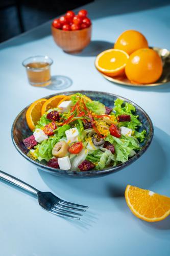 a salad in a bowl on a table with oranges at La baga Beach Hotel in Calangute