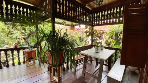 a wooden porch with a table and a potted plant at rumah kayu sulawesi antique in Bedugul