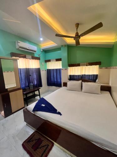 a bedroom with a large bed with a ceiling fan at Hotel Holiday Home in Digha