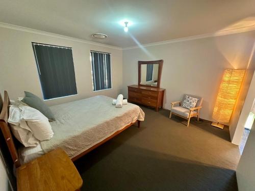 a bedroom with a bed and a mirror and a chair at Quiet Busselton Retreat in Busselton