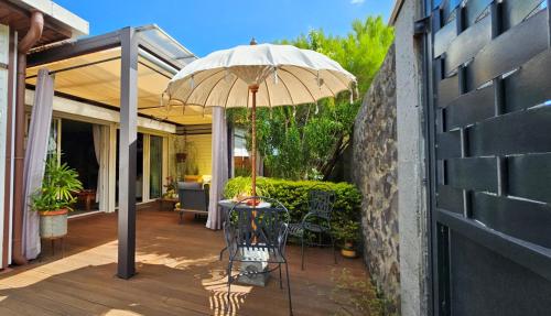 un patio con una mesa y una sombrilla en Villa YSANGA, en Saint-Pierre
