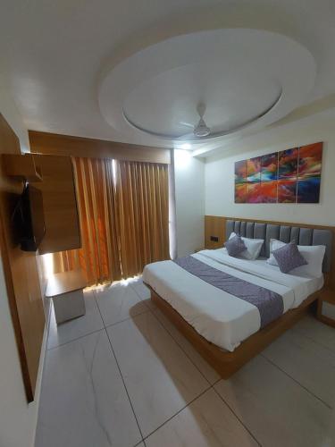 a bedroom with a large bed and a flat screen tv at HOTEL R K VILLA in Ahmedabad