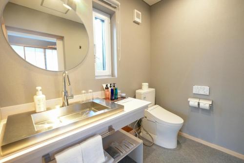 a bathroom with a sink and a mirror and a toilet at Kusatsu Onsen Kusatsu Hotel1913 in Kusatsu