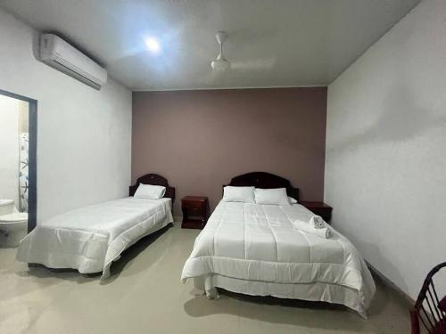 a bedroom with two beds with white comforters at Cabinas El Anzuelo #1 in Herradura