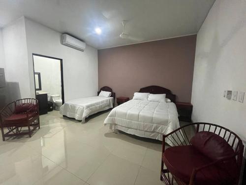 エラドゥーラにあるCabinas El Anzuelo #1のベッドルーム1室(ベッド2台、椅子2脚付)