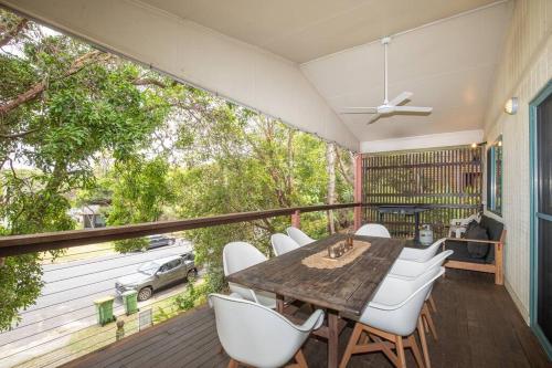 a balcony with a wooden table and white chairs at Tuckeroo + sleeps 10 + central in Point Lookout