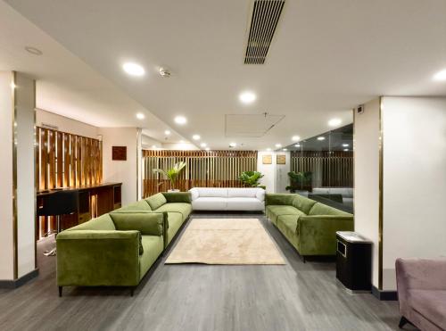 a living room with green couches and a piano at The Habitat Suites in Guruvāyūr