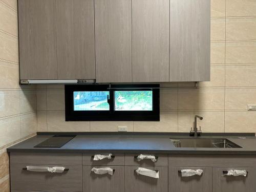a kitchen with a sink and a tv on the wall at 五星佶民宿 in Jinning