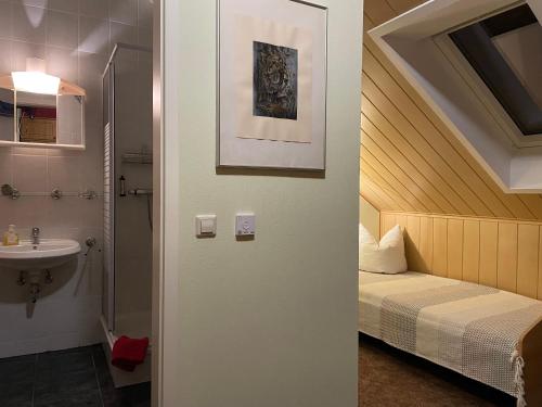 uma casa de banho com uma cama e um lavatório ao lado de um espelho em Pension Grasse & GenießerImbiss 