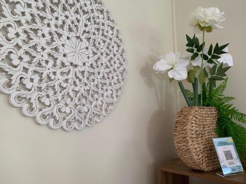 a vase of flowers on a table next to a wall at Le Clos des Bains Mauritius in Blue Bay
