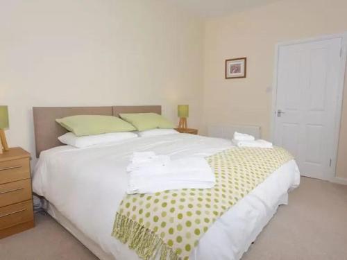 a bedroom with a large white bed with green pillows at Criffel View in Dumfries