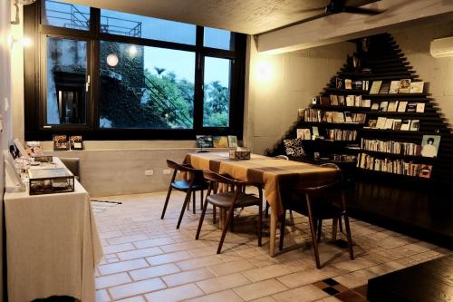 a dining room with a table and chairs and a book shelf at 6號交響曲民宿 in Chenggong