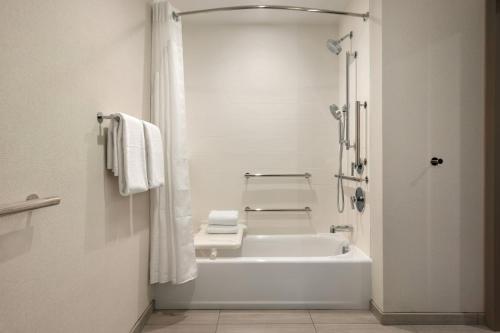 a white bathroom with a tub and a shower at Holiday Inn Express Cape Canaveral by IHG in Cape Canaveral