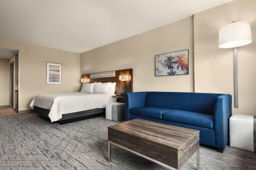 a hotel room with a bed and a blue couch at Holiday Inn Express Cape Canaveral by IHG in Cape Canaveral