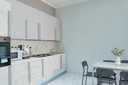 una cocina con armarios blancos y una mesa con sillas. en Hostel Partenope, en Nápoles