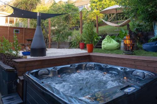 a hot tub in a backyard with a umbrella at Te Tupahipahi - The Sandspit in Nelson