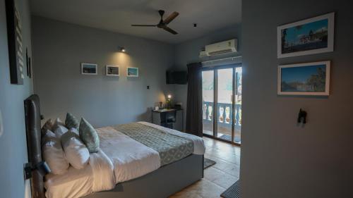 a bedroom with a bed and a ceiling fan at Sortby Stays, Vagator in Vagator