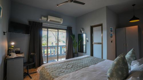 a bedroom with a bed and a window and a desk at Sortby Stays, Vagator in Vagator