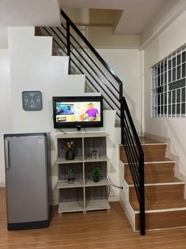 a living room with a staircase with a television and a stair case at ESTILO APARTMENT 2-storey in Clarin