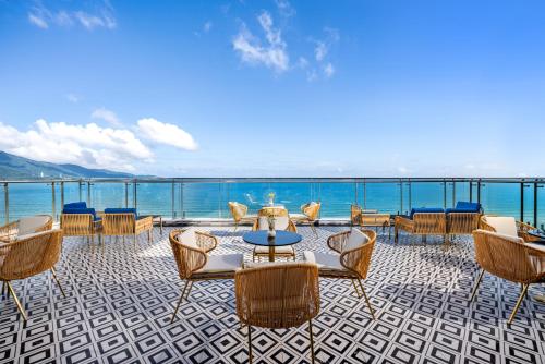 een patio met stoelen en een tafel en de oceaan bij BlueSun Danang Beach Hotel in Da Nang