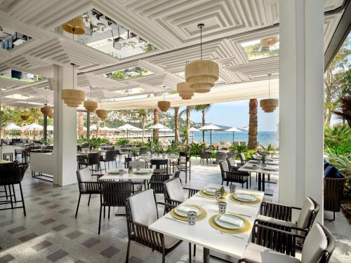 een restaurant met witte tafels en stoelen en de oceaan bij Caja by Maxx Royal in Bodrum City