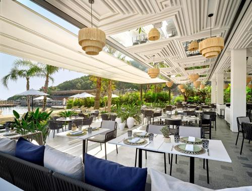 een restaurant met witte tafels en stoelen en palmbomen bij Caja by Maxx Royal in Bodrum City