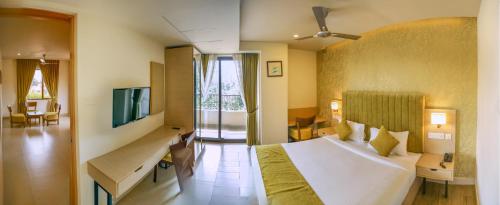 a hotel room with a bed and a television at Raj Riveria Hotel in Mūvattupula