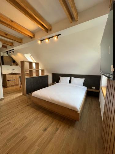a bedroom with a large white bed and wooden floors at Zlatni Odmor (Centar) in Zlatibor