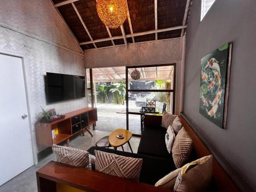 a living room with a couch and a tv at Lugadia Bungalow in El Nido