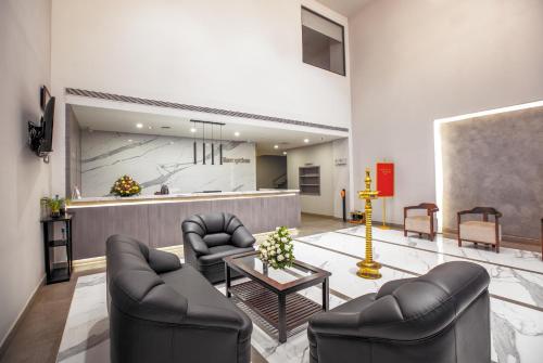 a lobby with two chairs and a table and a counter at Raj Riveria Hotel in Mūvattupula