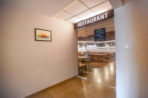 a dining room with a restaurant sign on the wall at Raj Riveria Hotel in Mūvattupula