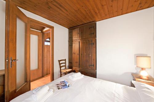 a bedroom with a white bed with a wooden ceiling at Appartamento La Fontaine Ski In Ski Out - Happy Rentals in Claviere