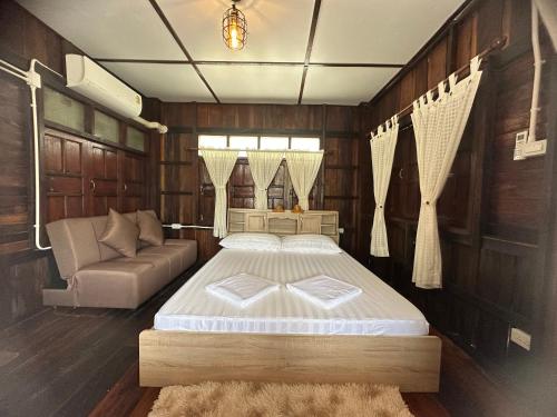 1 dormitorio con cama y sofá en ม่วนใจ๋ปันสุข โฮมสเตย์แอนคาเฟ่ Muanjai punsuk homestay and cafe, 