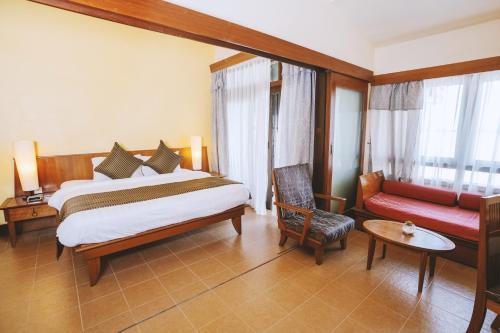 a hotel room with a bed and a couch at Ombak Villa Langkawi in Pantai Cenang