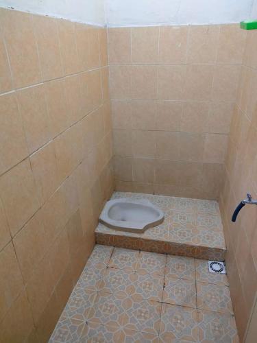a bathroom with a toilet in a tiled floor at Hutama Kaliurang Guest House in Soprayan