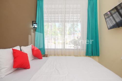 um quarto com uma cama com almofadas vermelhas e uma janela em Travelista Homestay near GOR Candradimuka Semarang Mitra RedDoorz em Srondolwetan