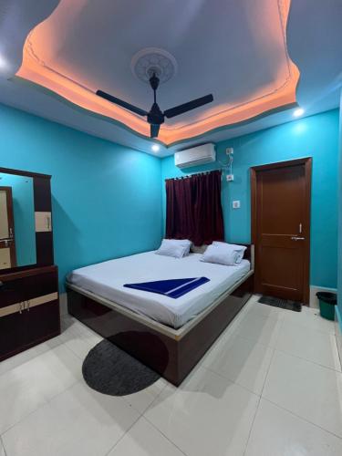 a bedroom with a bed and a blue wall at Hotel Holiday Home in Digha