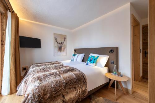 a bedroom with a large bed and a table at PAPILL'ON - Boutique Hotel in La Tzoumaz