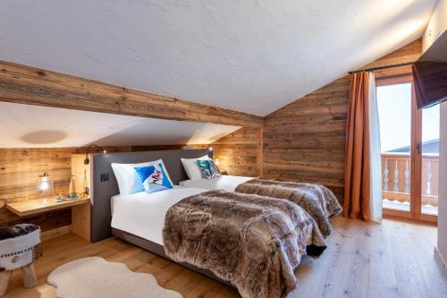 a bedroom with two beds in a room with wooden walls at PAPILL'ON - Boutique Hotel in La Tzoumaz