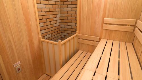 eine Sauna mit einer Bank und einer Ziegelwand in der Unterkunft Hotel Grand Ciel Hanamaki in Hanamaki