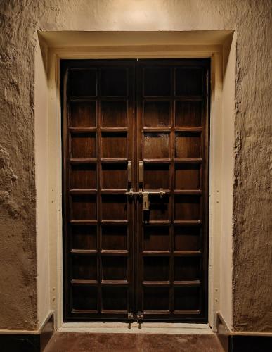 a wooden door in a stone wall with at Bastar Greens Eco Stays in Jagdalpur