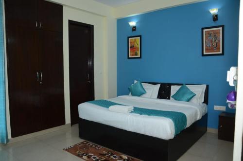 um quarto com uma cama grande e uma parede azul em Rumaisa Red em Noida