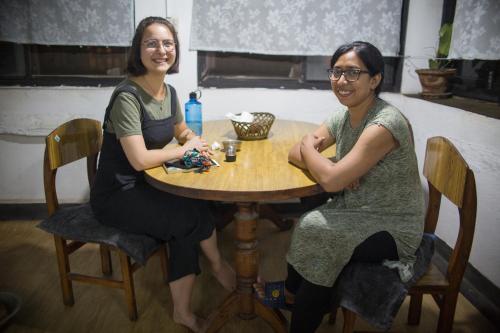two women sitting at a wooden table at Traditional Newari Homestay in Pātan