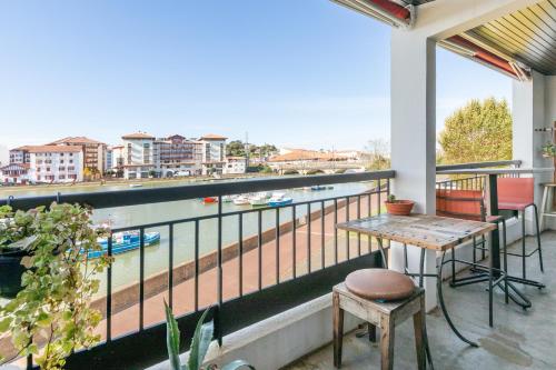 a balcony with a table and a view of a river at Vue plongeante sur l'eau in Saint-Jean-de-Luz