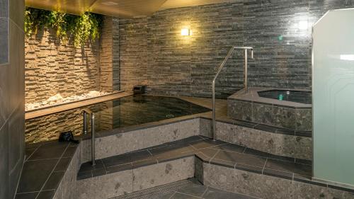 uma banheira de hidromassagem num quarto com uma parede de tijolos em Hotel Grand Ciel Hanamaki em Hanamaki