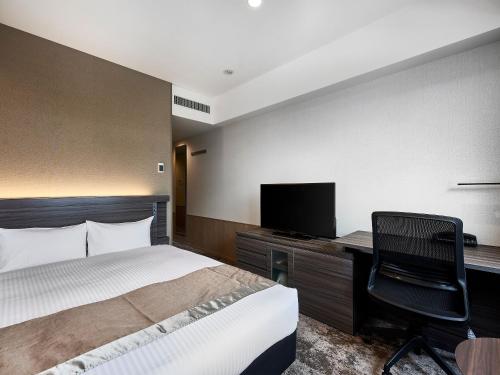 a bedroom with a bed and a desk and a television at DEL style Osaka-Shinsaibashi by Daiwa Roynet Hotel in Osaka
